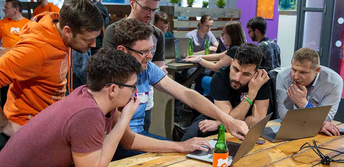 A group of the Smartbear team gathered around a laptop as part of the EuroSTAR 2019 meet-up
