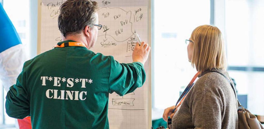 A test clinic doctor helping a EuroSTAR delegate solve a problem on a whiteboard