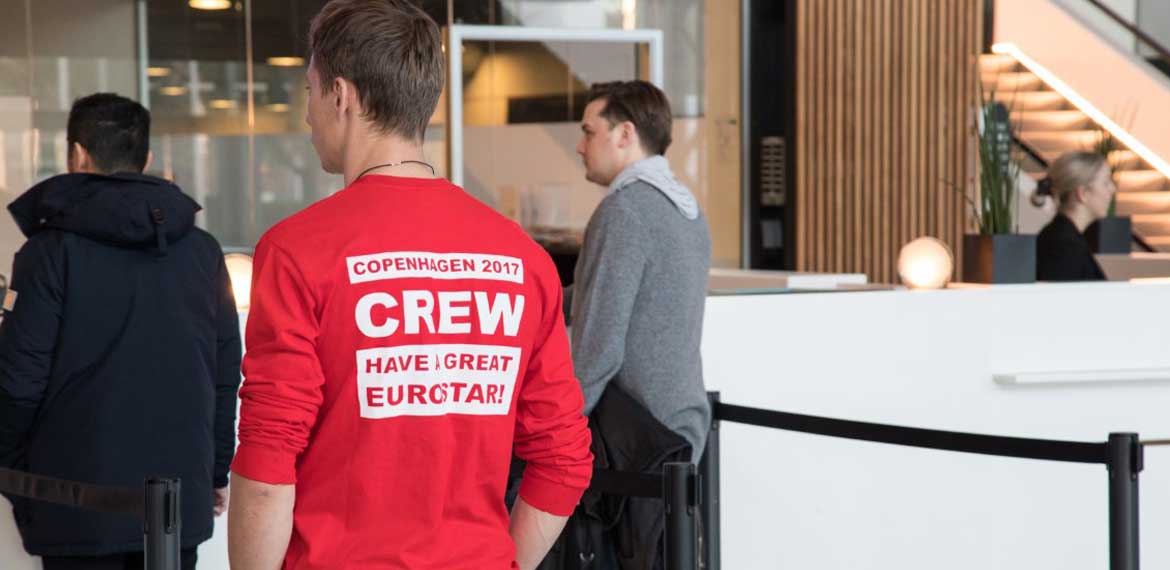 A EuroSTAR volunteer wearing a red t-shirt standing at the conference help desk