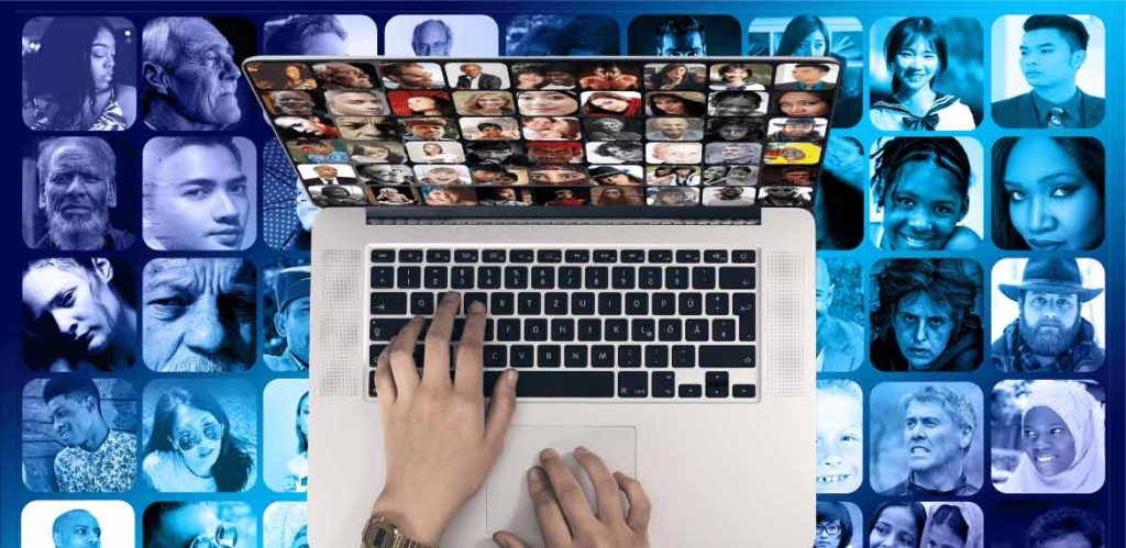 Laptop displaying lots of different faces on screen set against a dark blue background also displaying different faces