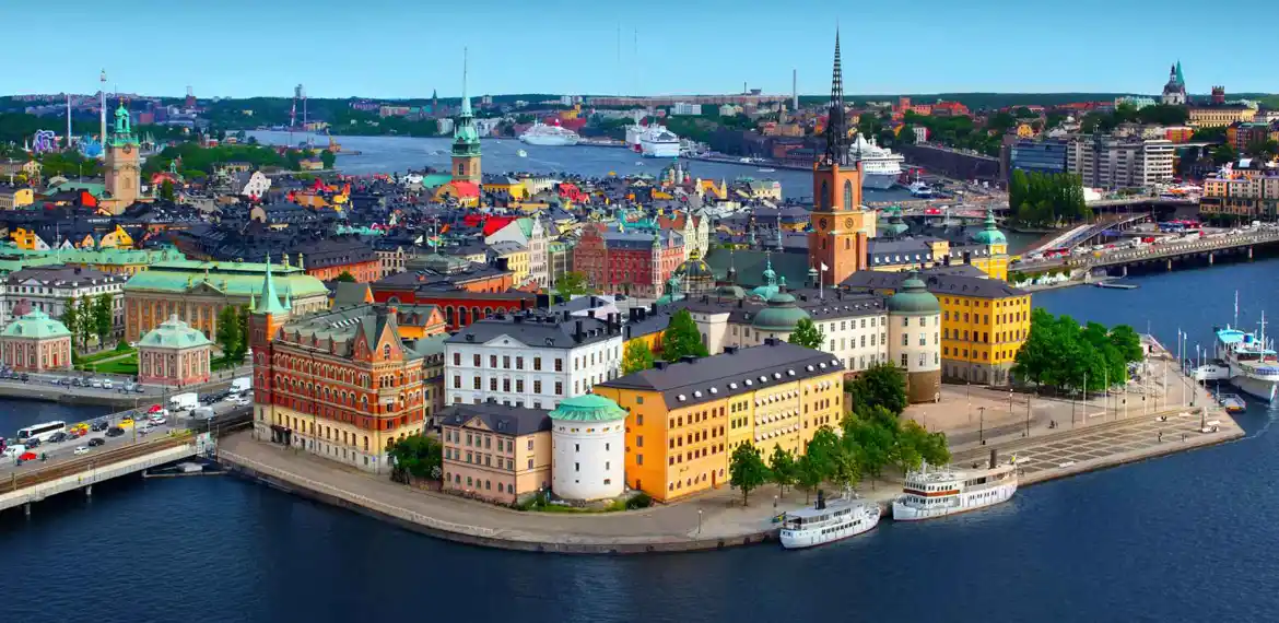 A landscape image of Sweden featuring colourful houses alongside a waterway